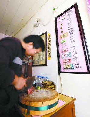 Preparing donkey burgers with price list in ancient Chinese coins hanging on wall